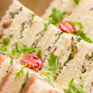 Close-up of assorted gourmet sandwiches with fresh arugula and tomatoes, perfect for catered events.