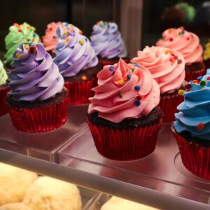 Delightful array of colorful cupcakes with vibrant icing and sprinkles in a bakery display.